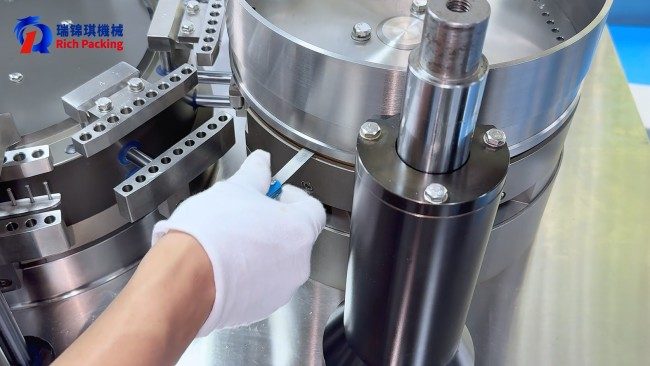 The operator is adjusting the gap between the dosing disc and the copper disc of the capsule filling machine.