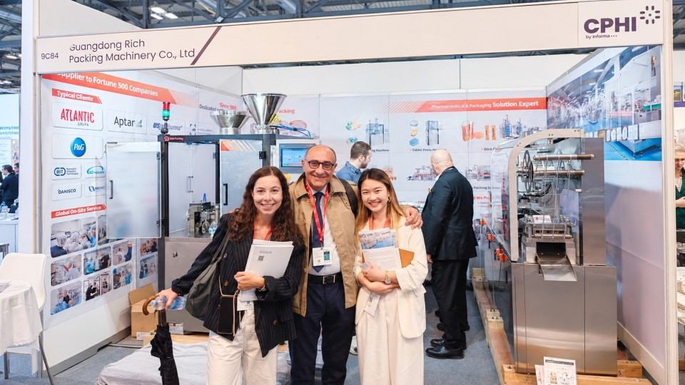 Visitors pose with Rich Packing staff in front of the machinery display